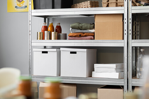 Organized garage or basement metal shelving with canned goods, neatly folded blankets, white storage bins, and labeled boxes for efficient home storage solutions